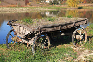 Fototapeta na wymiar Old and abandoned wooden traditional cart (wain) in far Ukrainian village in Kiev region. The ancient Ukrainian peasants transport, Ukrainian custom and traditions