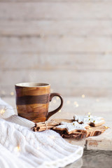 Mug of hot steamy tea, Christmas gingerbread cookies at wooden background with glares. Cozy morning breakfast with homemade sweets and cup of coffee. Winter food, drinks, new year lights.