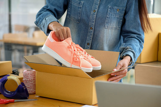 Online sellers are packing shoes in boxes to deliver to customers.