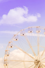 Ferris wheel on the colorful cloudy sky. Background concept of happy holidays time.