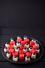Watermelon salad with feta cheese. Healthy salad with blueberries, watermelon and cheese. Summer salad on dark background. Dark and moody