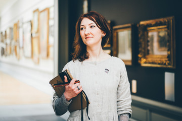 Young woman sketching in Museum. Blurred pictures at the backround.