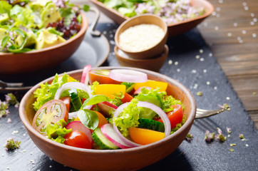 Vegetable salad of lettuce, cherry tomatoes, radish, cucumber, onion and basil on slate stone tray