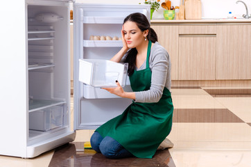 Young woman cleaning fridge in hygiene concept
