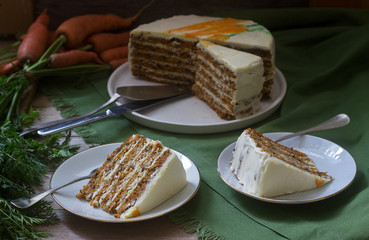 Carrot cake, pieces of cake with curd cream and carrots on a wooden background. Rustic style.