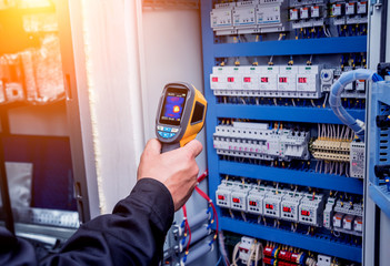 Technician use infrared thermal imaging camera to check temperature at fuse-box - obrazy, fototapety, plakaty