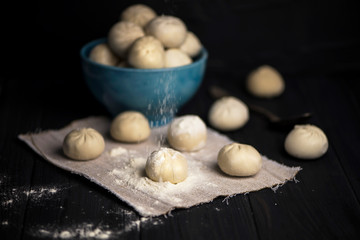 raw khinkali with meat filling on canvas on a dark wooden background