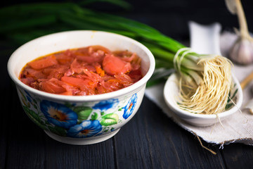 red beetroot soup and onions with garlic on a dark wooden background