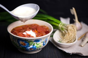 red beetroot soup and onions with garlic on a dark wooden background