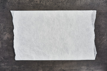 Crumpled piece of white parchment or baking paper on black concrete background. Top view. Copy space for text and design element.