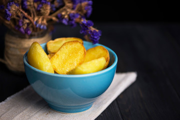 baked potatoes in a plate with wildflowers on a dark wooden background