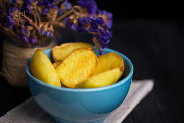 baked potatoes in a plate with wildflowers on a dark wooden background