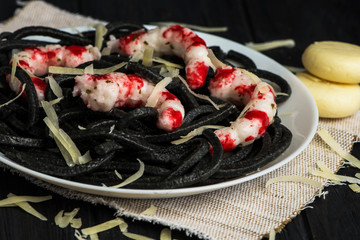 black spaghetti seaweed paste with large shrimp on a dark wooden background