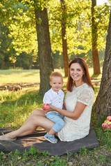 Fototapeta premium Autumn family walk in forest. Happy mother and baby boy. Family with little son in autumn park. Family and mother's day. Children Protection Day. Family picnic