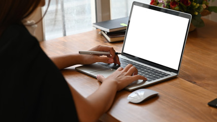 Cropped shot woman typing mockup laptop computer with blank screen.
