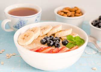 Breakfast. Oatmeal with bananas, strawberries, nuts and blueberries on the blue wooden bakground. Healthy breakfast. Close-up