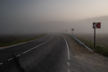 Big road with signs and morning fog
