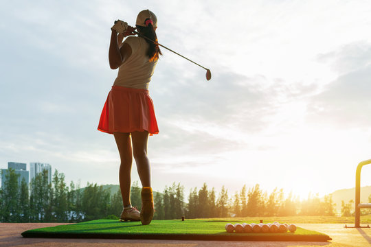 Woman driving practice golf or trainer at golf course on the fairway at sunset