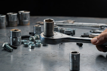 Close up automotive mechanic picking tools in garage