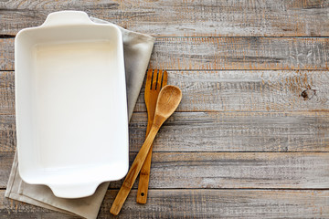 Ceramic white baking dish on a wooden old background.