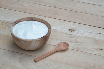 Natural homemade plain organic yogurt in wooden bowl and wood spoon on wood texture background