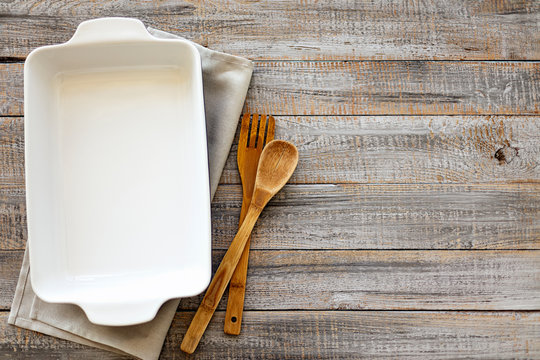Ceramic white baking dish on a wooden old background.