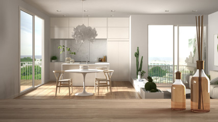Wooden table top or shelf with aromatic sticks bottles over blurred modern scandinavian minimalist living room with kitchen, white architecture interior design