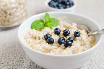 Healthy breakfast. porridge in a bowl with honey and berries and tea. Close-up