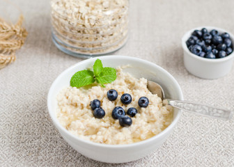 Healthy breakfast. porridge in a bowl with honey and berries and tea. Close-up