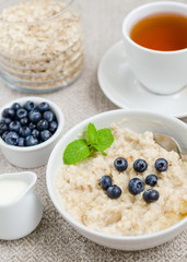 Healthy breakfast. porridge in a bowl with honey and berries and tea. Close-up