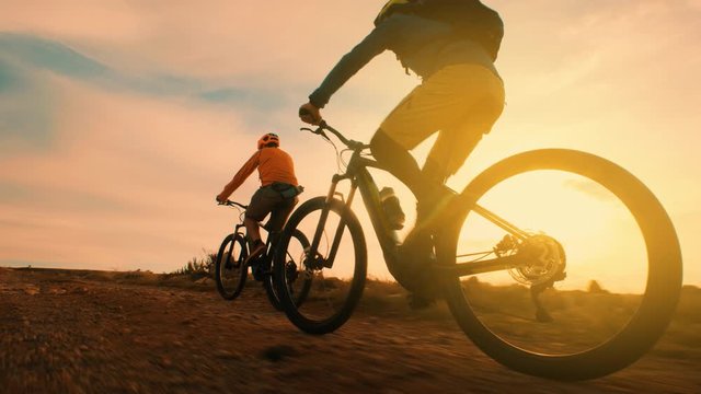 Silhouette of two guys riding bikes at sunset