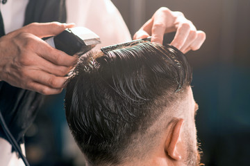Barbershop. Hairdresser performs a fashionable haircut for a man.