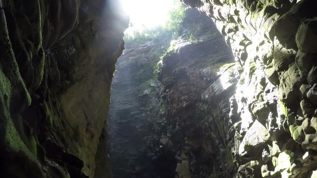 A cave in Canaima national park in Venezuela, with a big hole in the roof and water drops dropping down.