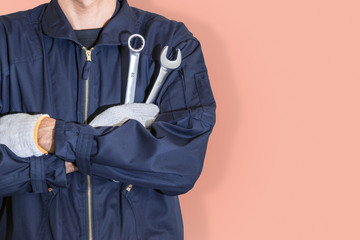 Car repairman wearing a dark blue uniform standing and holding a wrench that is an essential tool for a mechanic isolated on colorful pastel background, with clipping path.