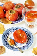 ripe juicy persimmons on a light background. You can eat with spoons like jelly. autumn still life flat. autumn leaves.