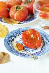 ripe juicy persimmons on a light background. You can eat with spoons like jelly. autumn still life flat. autumn leaves.