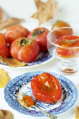 ripe juicy persimmons on a light background. You can eat with spoons like jelly. autumn still life flat. autumn leaves.