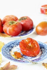 ripe juicy persimmons on a light background. You can eat with spoons like jelly. autumn still life flat. autumn leaves.