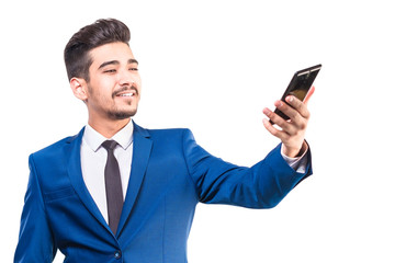 Аttractive man in a blue suit looking at the phone's screen on a white background. Isolated.