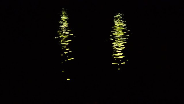 Two sets of green lights reflected from the sea water, creating a scene that looks like two green demon eyes. 