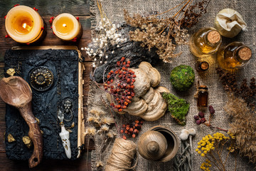 Book of magic and different dried herbs on the table.