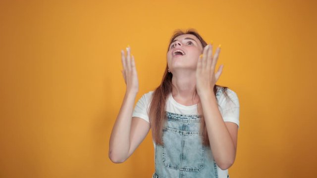 Young woman wearing white t-shirt, over orange background shows emotions