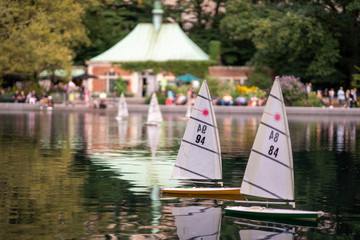 model sailboats in park pond with boathouse in background
