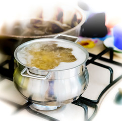 Metal pot with pasta and boiling water on the kitchen burner