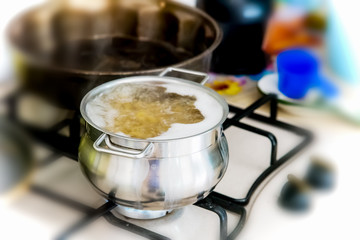 Metal pot with pasta and boiling water on the kitchen burner