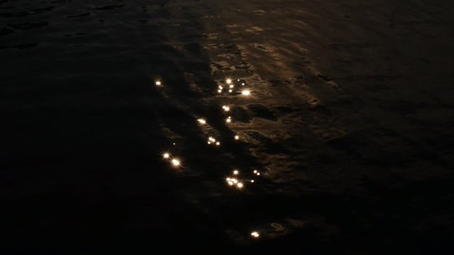 Sunlight like popping stars reflected from black lake water.