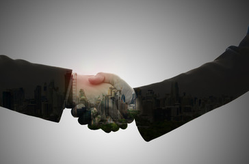 Double exposure of business handshake on abstract city background.Teamwork concept,Partners shaking hands.