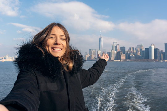 happy woman taking a selfie from the new york ferry, city skyline as background