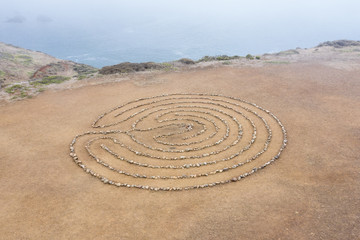 Fototapeta na wymiar A circular rock labyrinth is found on the edge of the Pacific Ocean just north of San Francisco, California. Labyrinths symbolize the journey through life from birth to spiritual awakening to death.