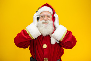 Santa Claus dancing on yellow background. Santa Claus wearing headphones. Christmas party concept with music.